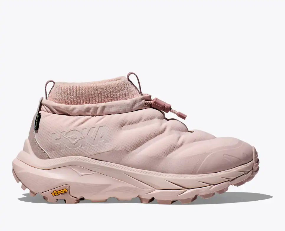 Light pink slip-on shoe with a quilted, insulated design and a ribbed ankle collar. Features a toggle fastener and a chunky, textured Vibram sole for traction.